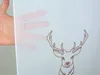 A hand is held up against a white background, partially obscuring a brown embroidered deer design. Produktbild-Vorschau