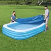 A couple is putting a blue cover on an inflatable pool in a grassy yard. Produktbild-Vorschau