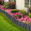 A garden border made of gray palisades separates a manicured lawn from a flower bed with pink and red flowers, and green bushes. The house wall is visible in the background. Voir les images du produit