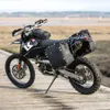 A black adventure motorcycle equipped with saddlebags and a tank bag is parked on a wooden walkway near a body of water. Produktbild-Vorschau