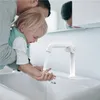 A father is helping his young child wash their hands at a sink with a modern white faucet. Produktbild-Vorschau