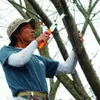 A man is pruning a tree branch with a folding saw. Produktbild-Vorschau