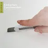 A hand is shown using a utility knife to cut a white foam material. Text overlays provide instructions. Produktbild-Vorschau