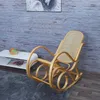 A rocking chair is placed on a rug in front of a white table and a wood-paneled wall. Voir les images du produit