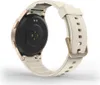 The back of a smartwatch with a white strap and gold accents is shown against a white background. Voir les images du produit