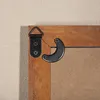 Close-up of the back of a wooden picture frame showing hanging hardware attached to the frame. Anteprima dell’immagine prodotto