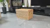 A wicker chest is placed on a tiled floor in front of a fireplace and a media console. Voir les images du produit