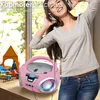 A young woman is listening to music on headphones while standing next to a pink CD player. Voir les images du produit