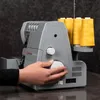 A hand is shown adjusting a dial on a gray Singer sewing machine with yellow thread spools on the side. Produktbild-Vorschau