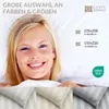 A woman is lying in bed with bedding, with product size and brand information displayed. Produktbild-Vorschau