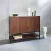 A wooden sideboard with decorative items on top and books on the shelf below, set against a concrete wall. Produktbild-Vorschau