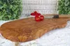 A rustic olive wood cutting board with cherry tomatoes and a knife on a white textured surface, with greenery in the background. Produktbild-Vorschau