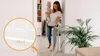 A woman is holding a baby and walking through a doorway with a baby gate installed. A close-up inset shows a detail of the gate. Voir les images du produit
