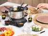A family fondue set is being used at a table with various food items and dipping sauces. Produktbild-Vorschau