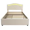 A beige upholstered bed frame with a slatted base and a curved headboard with integrated yellow LED lighting, shown from the front on a white background. Produktbild-Vorschau