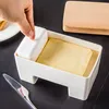 A hand is placing a lid on a butter dish containing a block of butter. A knife and a wooden lid are also visible. Podgląd zdjęcia produktu