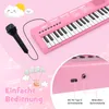 A pink toy keyboard with a microphone and cartoon clouds and sun. Produktbild-Vorschau