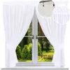 A white sheer curtain is draped across a window, revealing a lush green garden scene outside. Produktbild-Vorschau