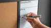 A hand is writing on a whiteboard attached to a corkboard. Podgląd zdjęcia produktu