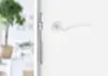 Close-up of a white door handle and lock mechanism on a white door. Produktbild-Vorschau