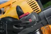 A gloved hand is shown pressing a button on a yellow and black leaf blower. Produktbild-Vorschau