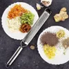 A grater is shown on a dark surface with various grated ingredients on plates. Produktbild-Vorschau