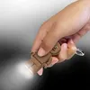 A hand holding a LEGO gingerbread man keychain with a light emitting from its feet. Produktbild-Vorschau