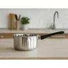 A stainless steel saucepan with a black handle sits on a countertop in a kitchen setting. The background shows a tiled backsplash, a faucet, and some kitchen utensils. Produktbild-Vorschau