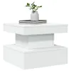 A white modern coffee table with books and a plant on top. Voir les images du produit