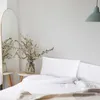 A bedroom scene with a bed, pillows, and a vase of flowers. Produktbild-Vorschau