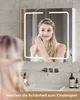 A woman is looking into a lighted mirror cabinet in a bathroom, with a sink and faucet visible below. Voir les images du produit