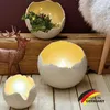 Decorative egg-shaped candle holders and a deer figurine on a wooden surface. Produktbild-Vorschau