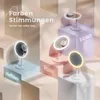 Four makeup mirrors in different colors are displayed on tiered pedestals, each labeled with its color name. Podgląd zdjęcia produktu
