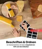 Hände beschriften einen Glas-Spaghettibehälter mit einem schwarzen Tafel-Etikett und weißem Kreidemarker, umgeben von anderen Behältern und Etiketten Produktbild-Vorschau