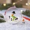 A snowman ornament being assembled in a snowy scene with Christmas lights in the background. Produktbild-Vorschau