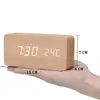 A hand is holding a wooden digital clock with dimensions indicated by text overlays. Produktbild-Vorschau