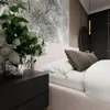 A bedroom scene with a bed, nightstand, and floral arrangement. Náhled obrázku produktu