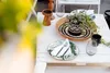 A table setting with plates, cutlery, glasses, and a potted plant. Náhľad obrázku produktu