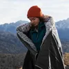 A woman wrapped in a blanket in a mountainous outdoor setting. Produktbild-Vorschau