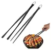 A hand is using a pair of black kitchen tongs to turn food on a grill. Produktbild-Vorschau