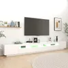 A modern white TV stand with LED lighting, a large flat-screen TV mounted above it, and decorative items on the stand and a shelf. Náhled obrázku produktu