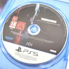 A close-up view of a PlayStation 5 game disc for Hitman World of Assassination, showing the disc's surface with game title, age rating, and console logo. Náhľad obrázku produktu