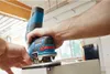 A person is using a Bosch router tool on a piece of wood in a workshop. Anteprima dell’immagine prodotto