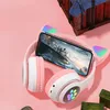 A pair of pink and white cat-ear headphones with a smartphone displaying a game, placed on a pink background. Náhľad obrázku produktu