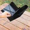 A hand is shown adjusting a portable charcoal grill on a wooden table outdoors. Náhled obrázku produktu
