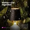 A black lamp with water droplets on it, set against a dark green leafy background, with rain falling. Anteprima dell’immagine prodotto