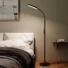 A floor lamp is positioned next to a bed in a bedroom. Náhled obrázku produktu