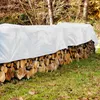 A stack of firewood covered by a white tarp in an outdoor setting. Náhled obrázku produktu