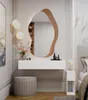 A modern bedroom vanity area with a floating desk, an abstract mirror, and a stool. Produktbild-Vorschau