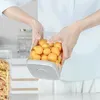 A person is holding a clear plastic food storage container filled with small orange fruits. Produktbild-Vorschau